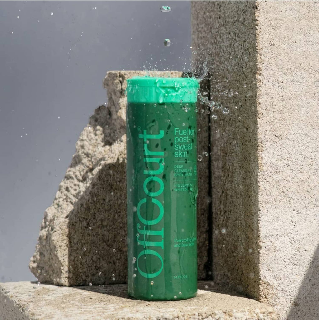 Offcourt green shower gel bottle on rocks with water droplets