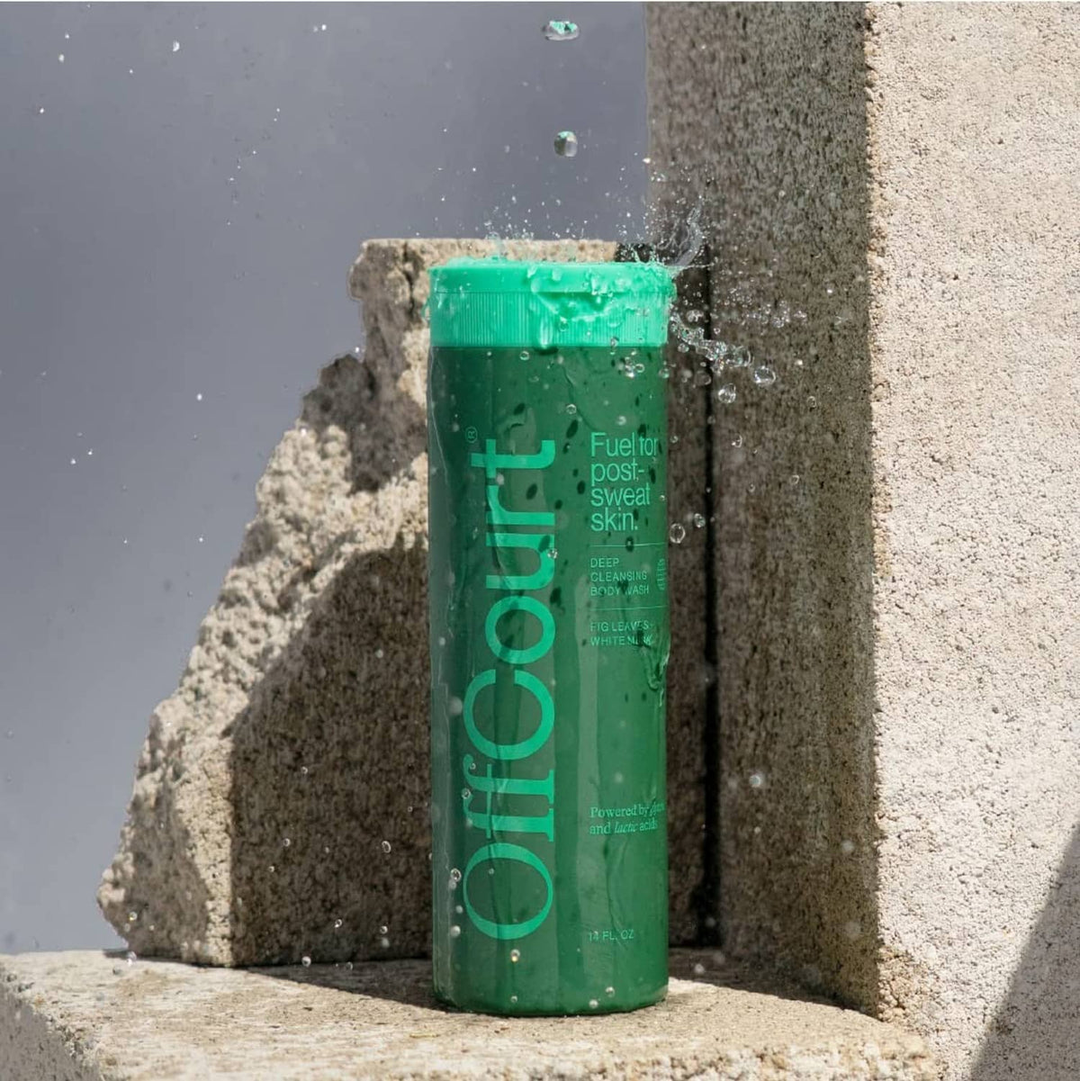 Offcourt green shower gel bottle on rocks with water droplets
