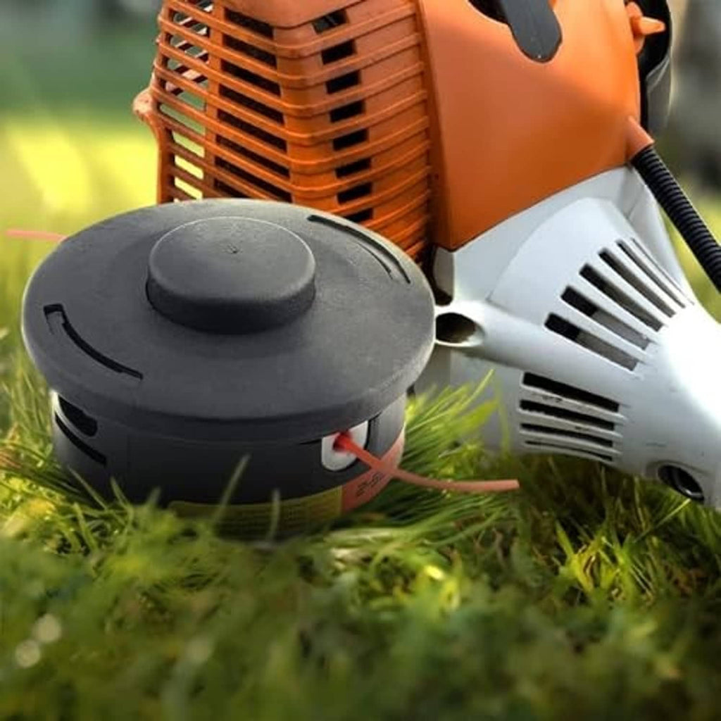 Black trimmer head on grass, orange cutting line feeding from trimmer