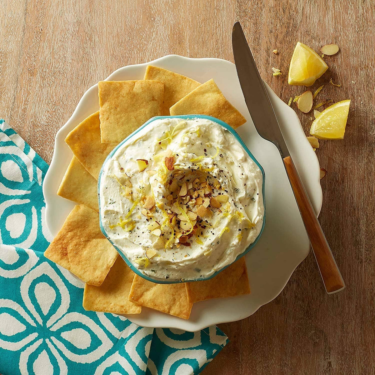 Baked pita chips with creamy white dip and lemon garnish in a bowl