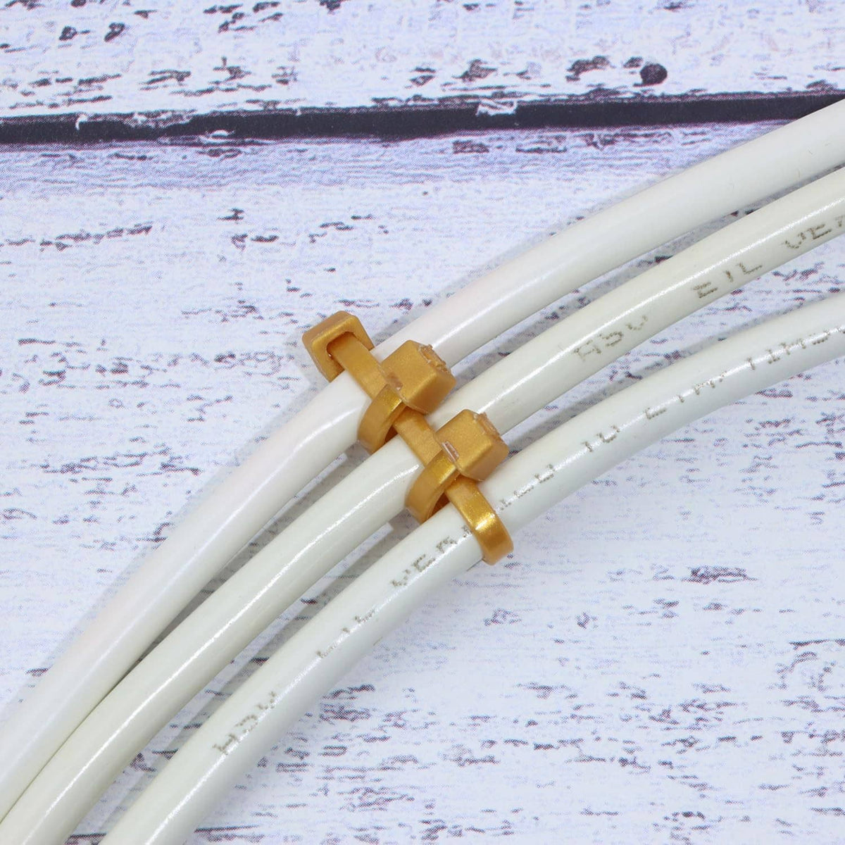 Gold nylon zip cable ties securing white cables, close-up