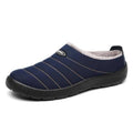 Dark blue slip-on house slippers with white faux-fur lining and stitched stripe panels