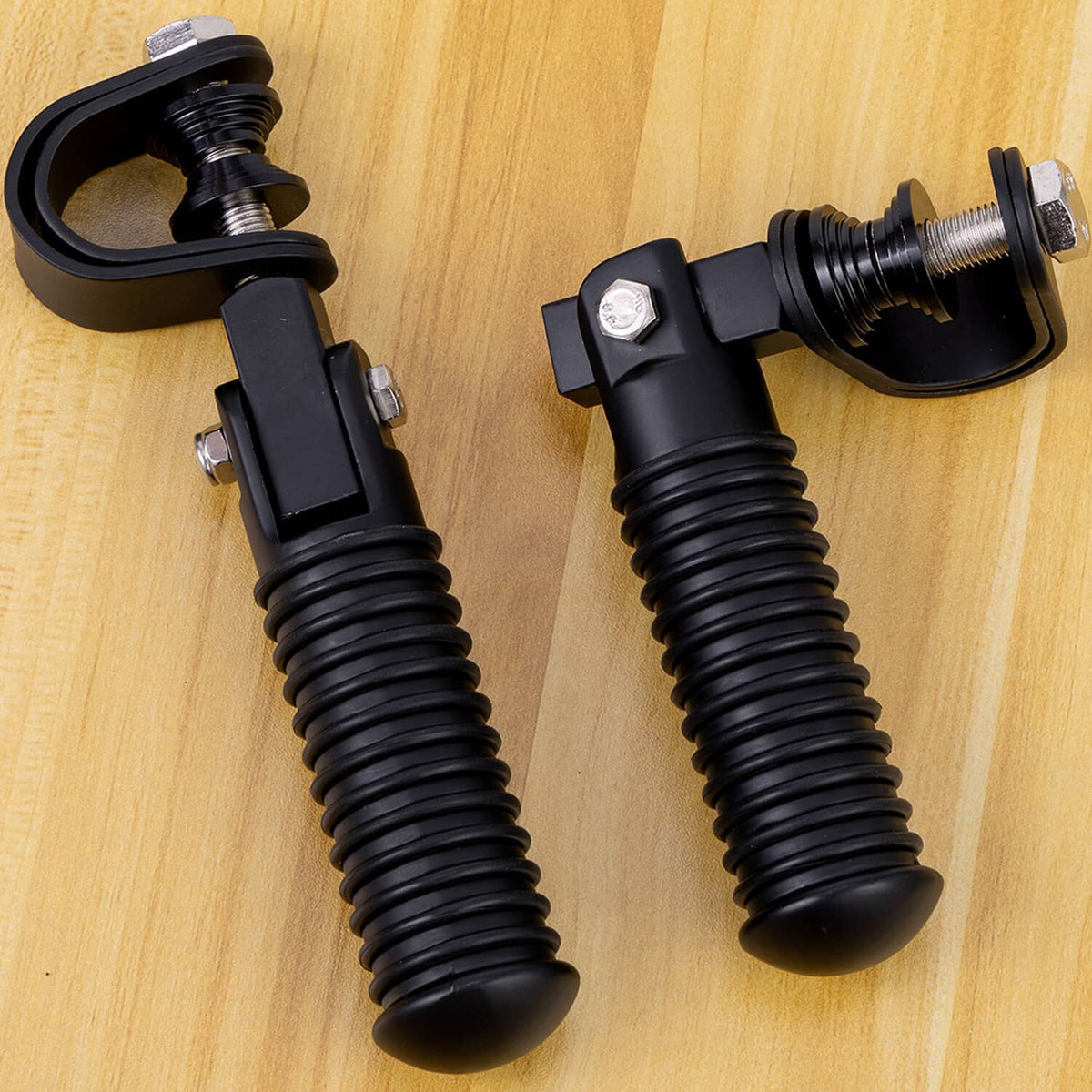 Black crash foot pegs with ribbed rubber grips and bolt hardware on wooden surface
