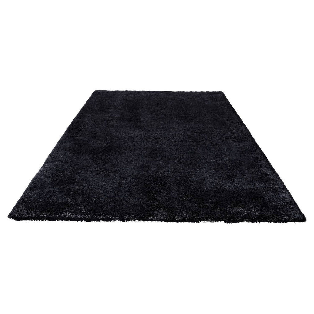 Black plush indoor area rug with shaggy low-pile texture, flat woven appearance