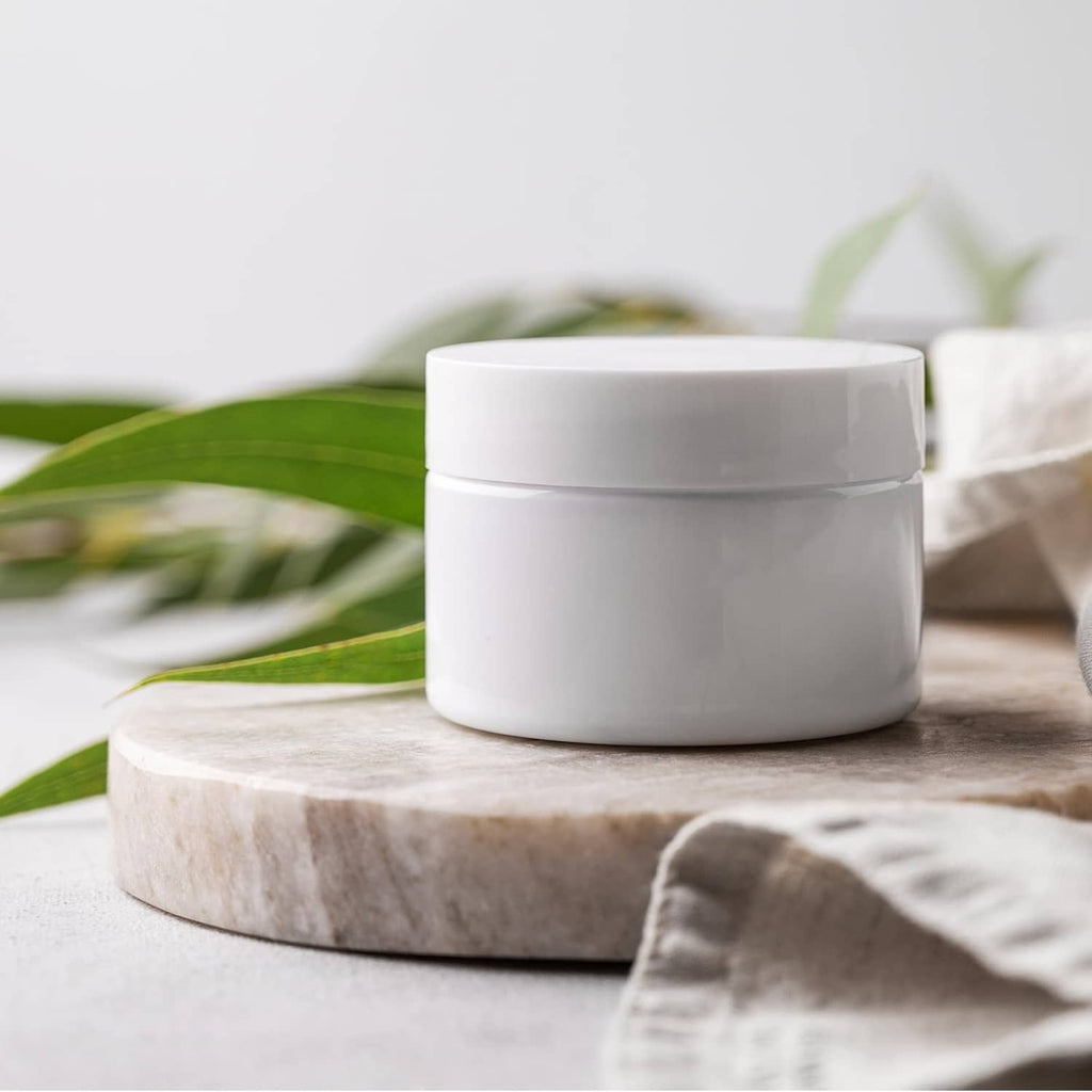 Aluminum bottle cap liners with white-lidded glass jar on wooden surface