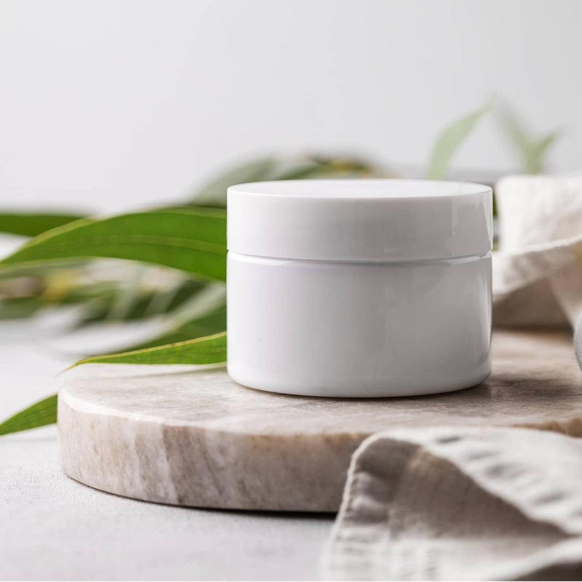 Aluminum bottle cap liners with white-lidded glass jar on wooden surface