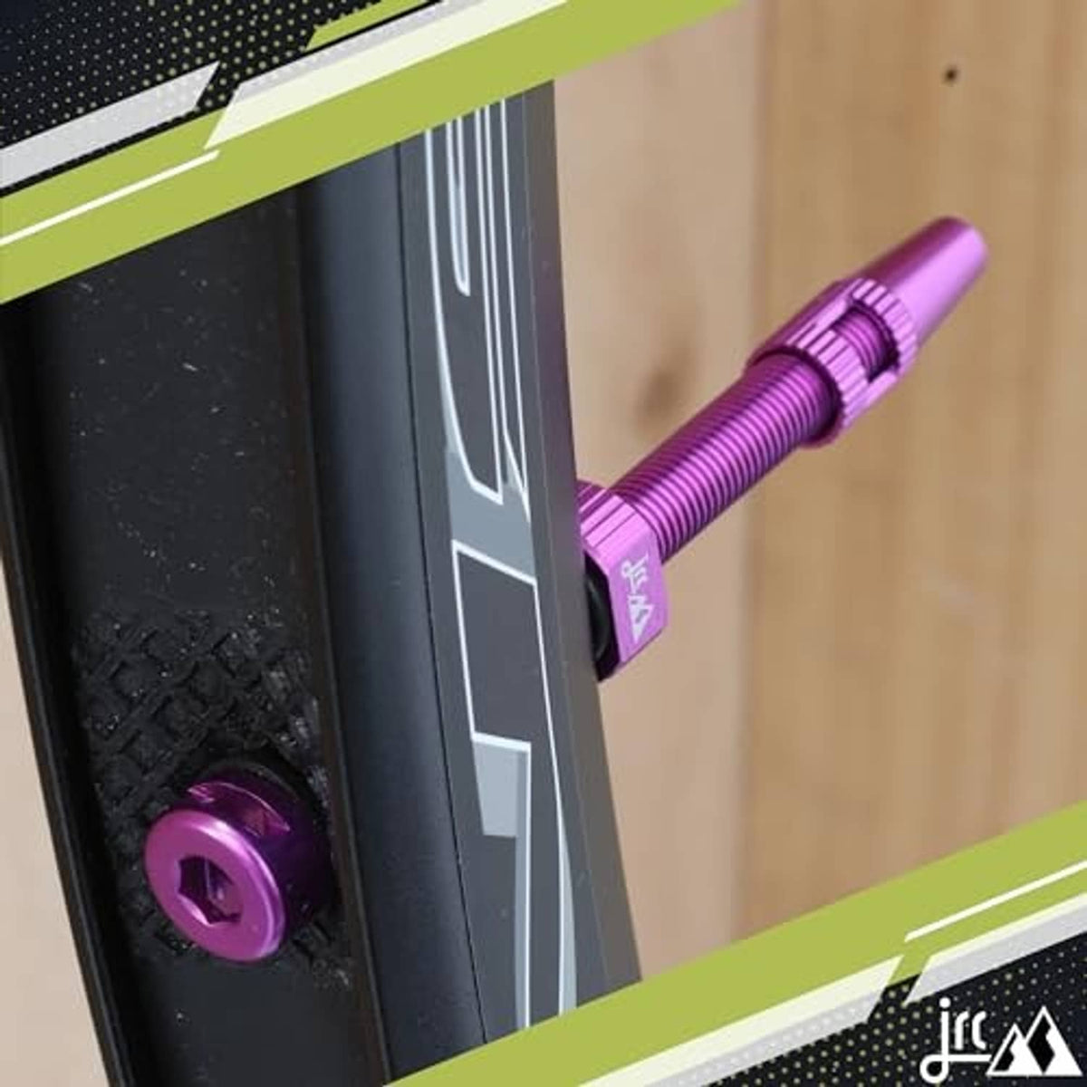 Purple anodized Presta tubeless valve stem inserted on a bicycle wheel by hand.