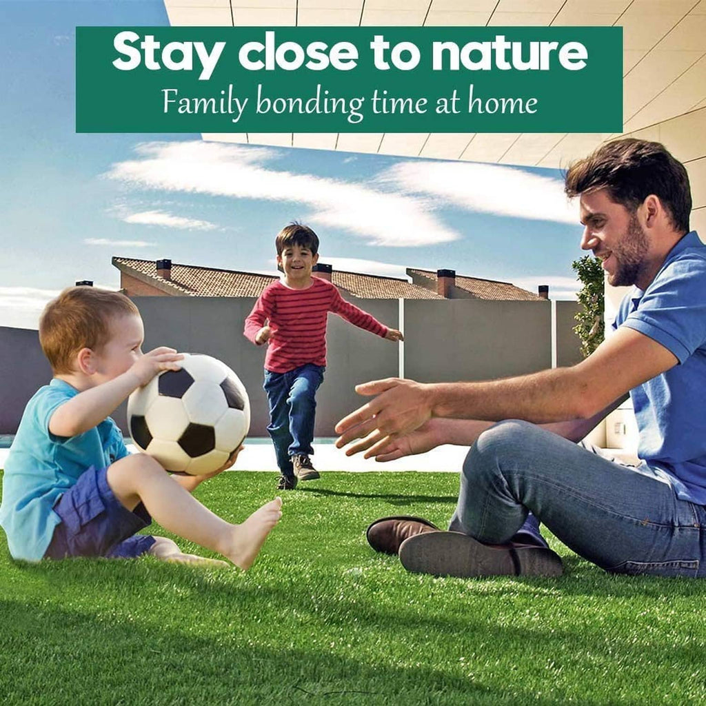Green artificial grass lawn in use, with a family playing and sitting on turf