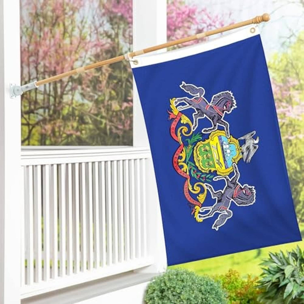 Blue embroidered Pennsylvania state flag hanging outdoors with coat of arms and horses