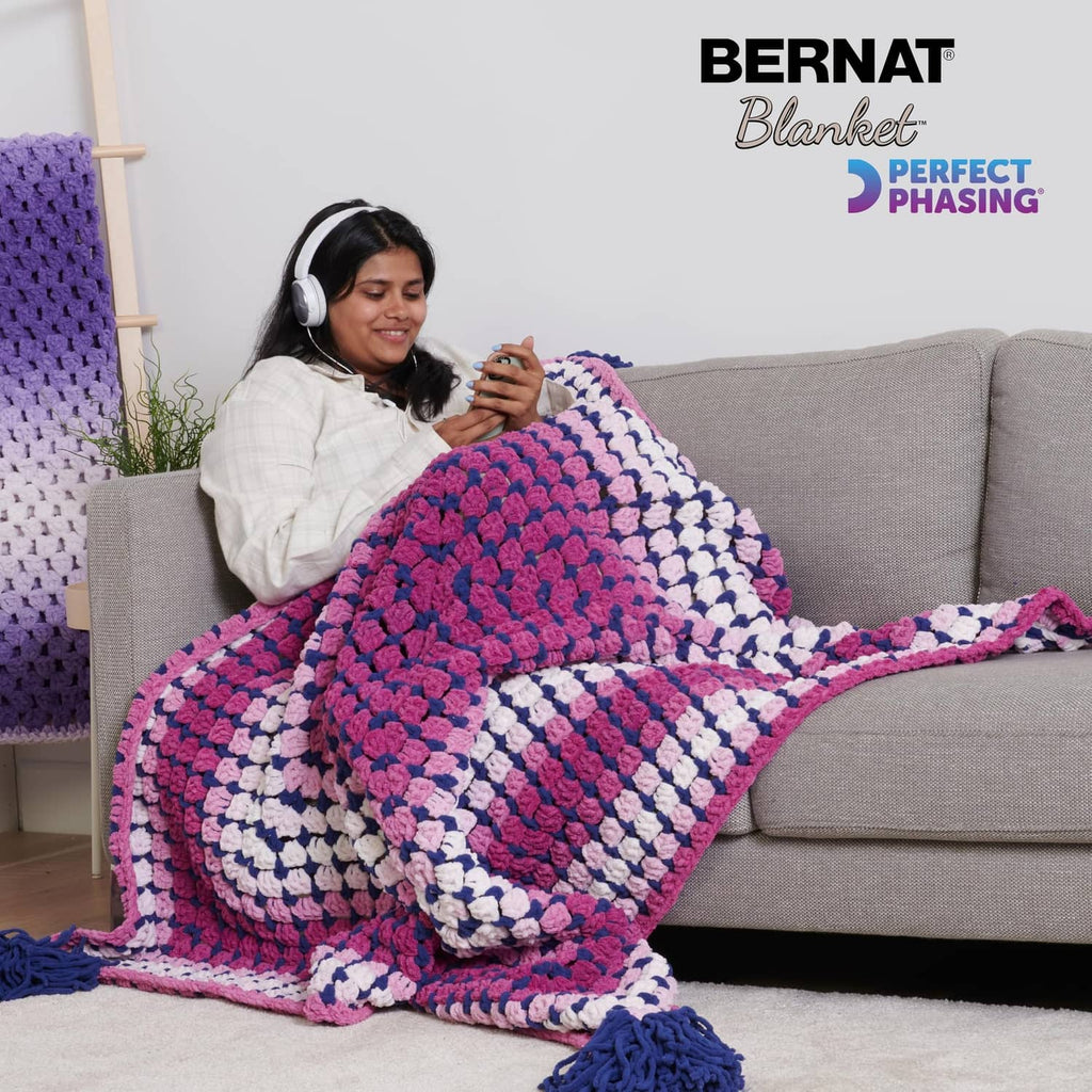 Crocheted gradient throw blanket in pink, purple, white, and blue with fringe