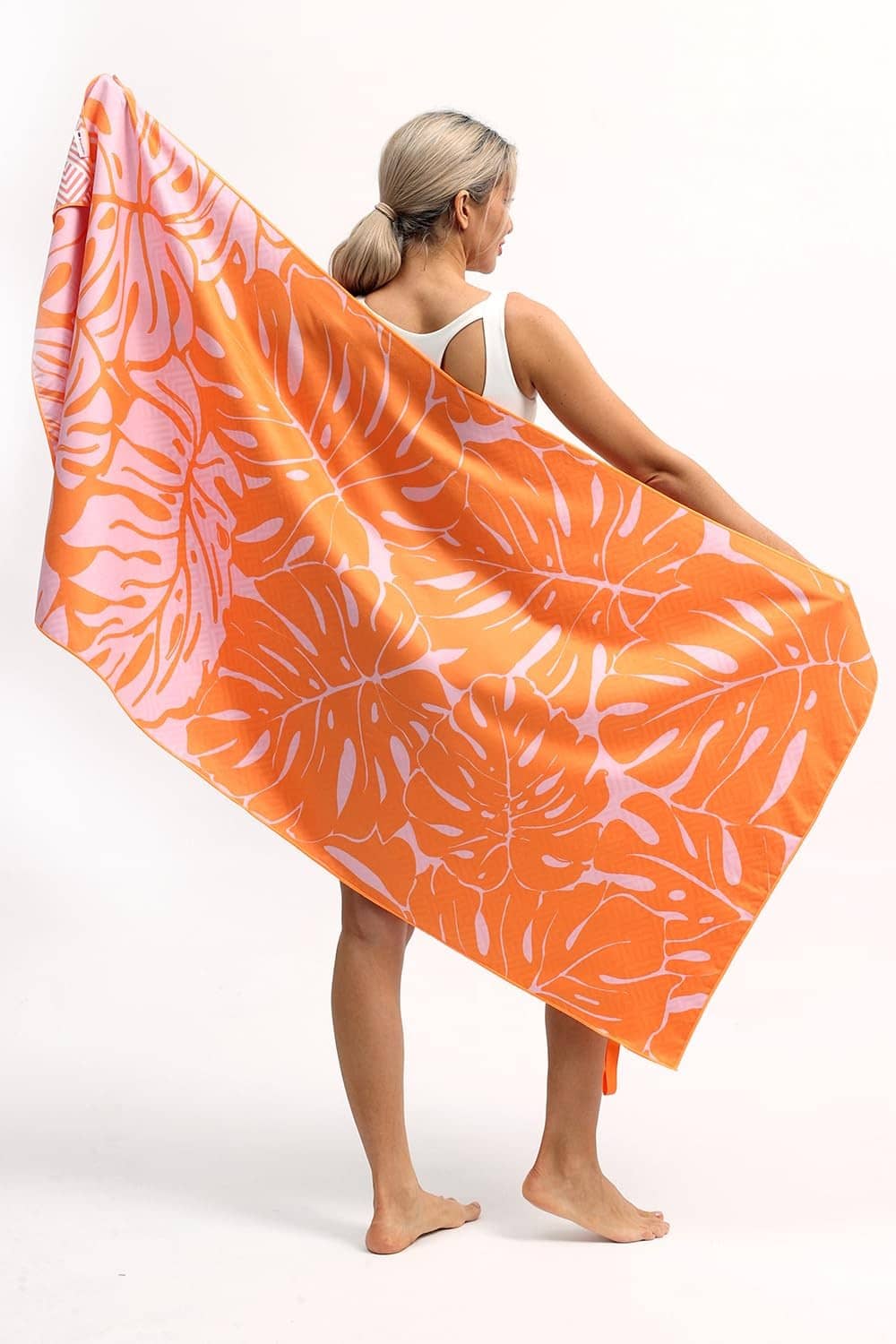 Orange beach towel with white palm leaf pattern, draped over shoulders on a person.