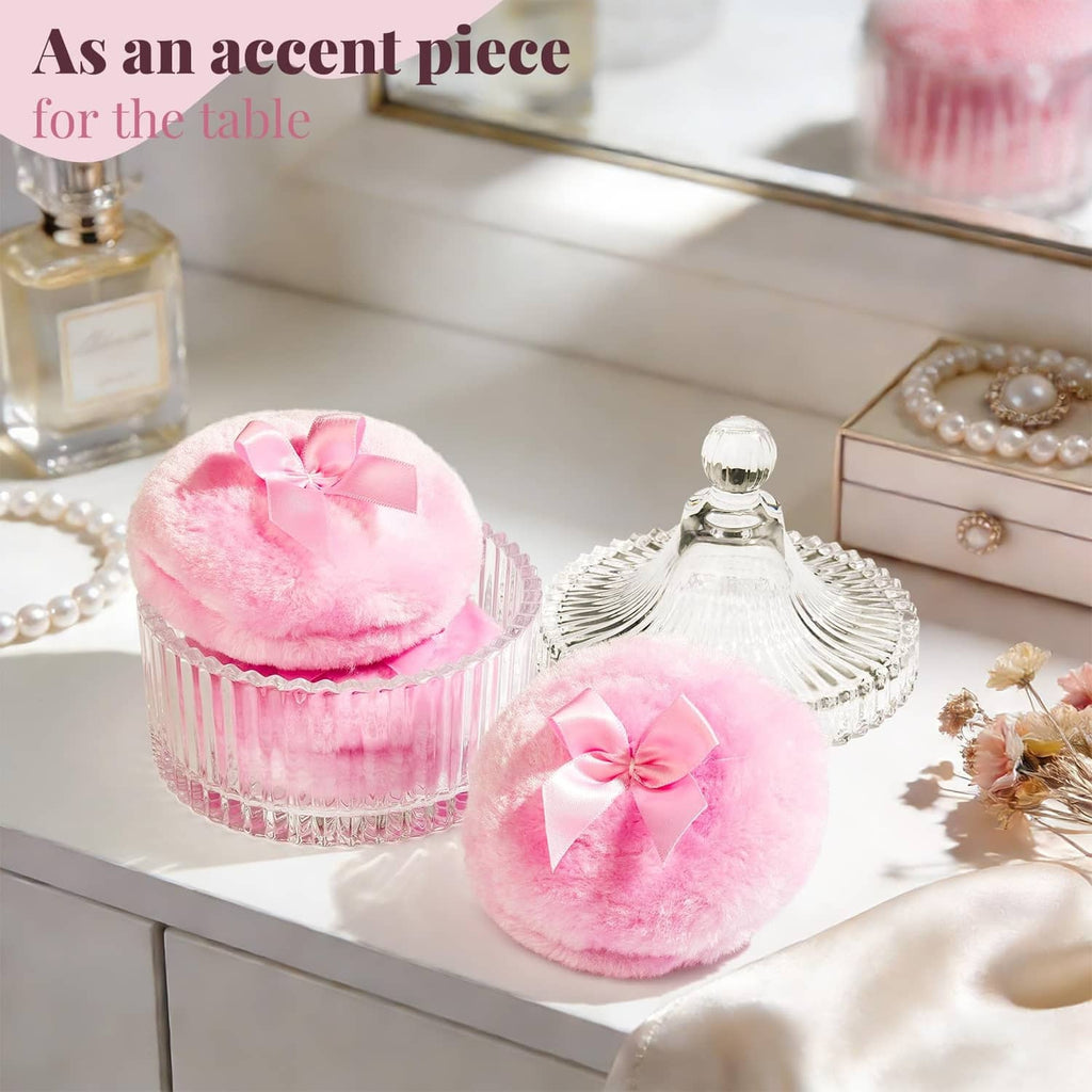Pink fuzzy powder puff with satin bow, with matching clear jar on a vanity