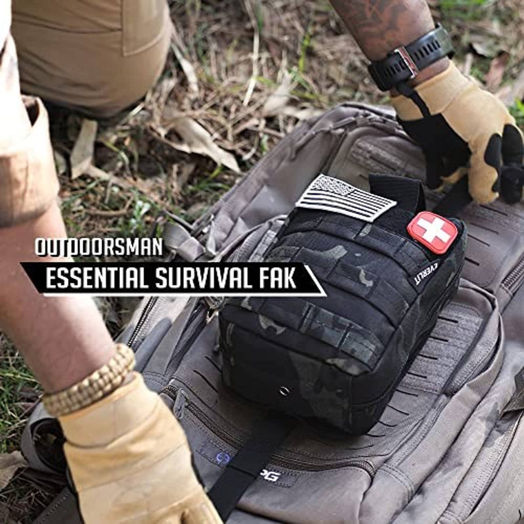 Dark tactical first aid pouch with red cross patch on ground with strap details