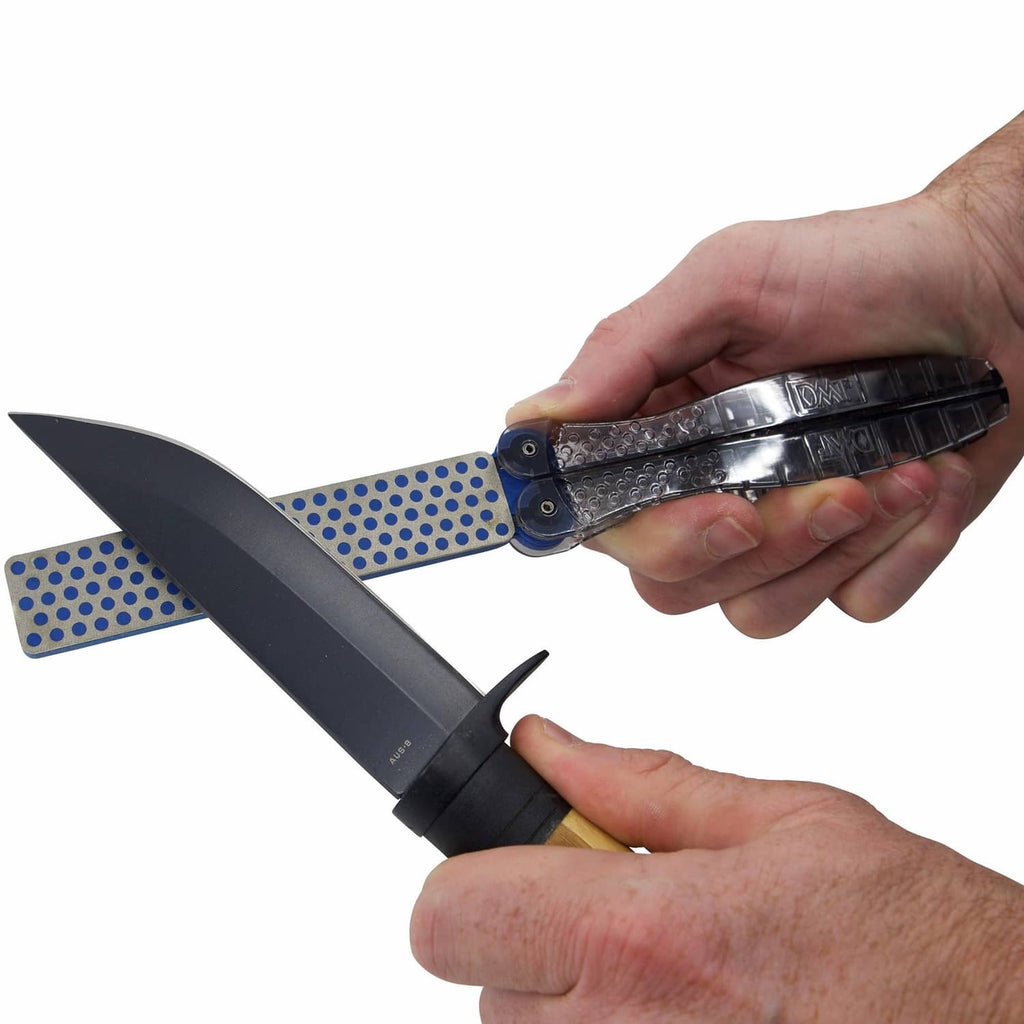 Hands using a portable double-sided sharpening stone with folding guide