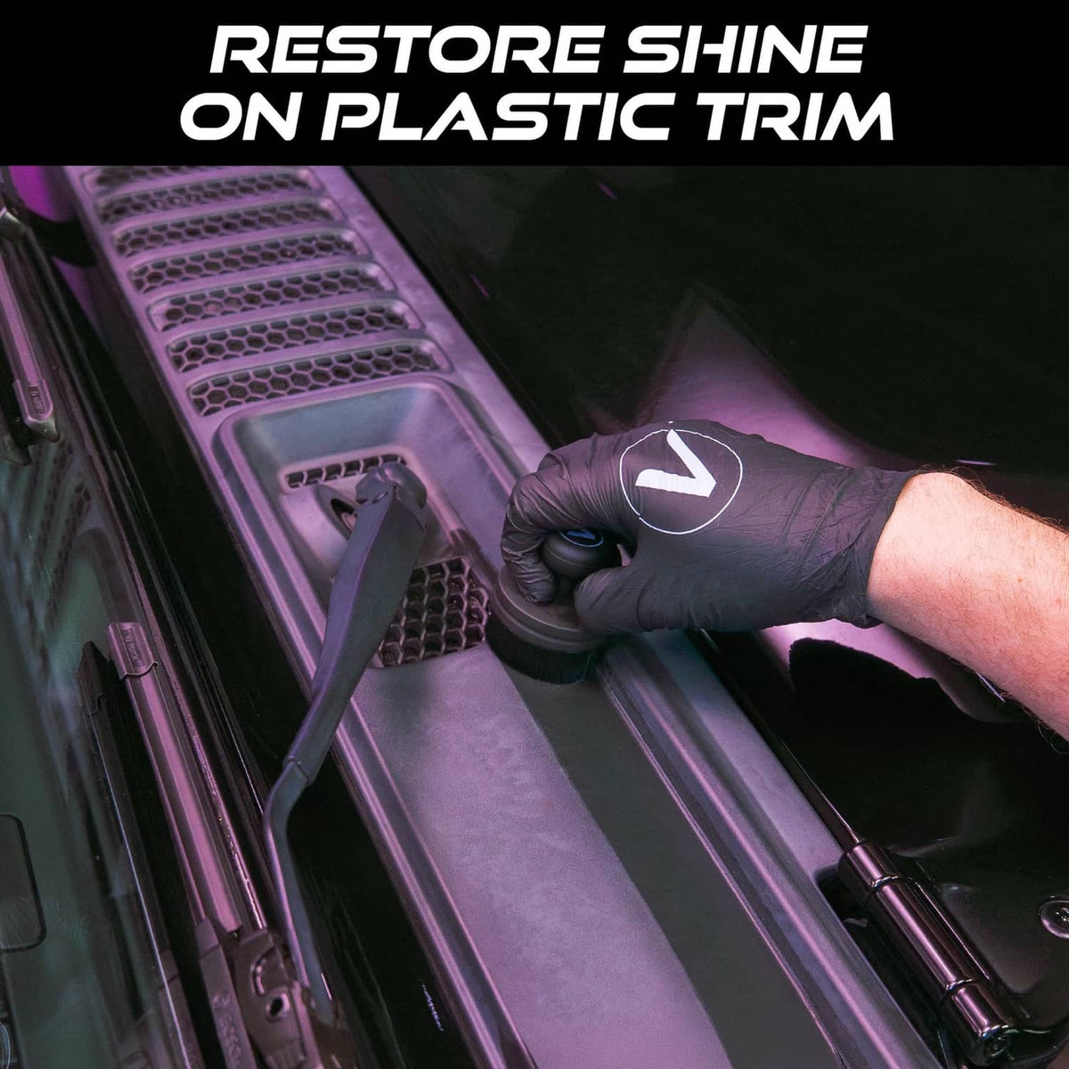 Tire shine applicator brush with black bristles working on dark vehicle plastic trim
