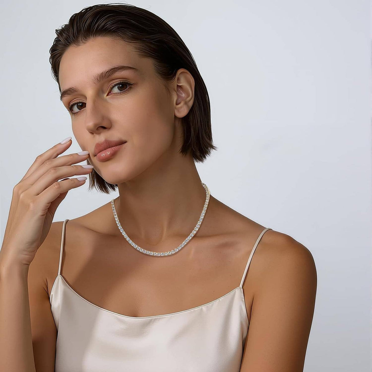 CZ tennis necklace worn at neckline, round clear stones on a gold-plated chain