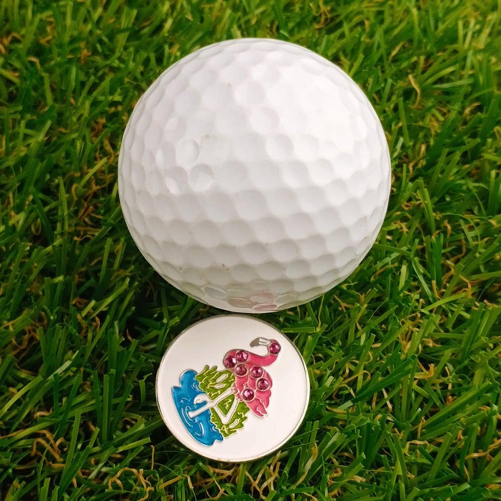 Flamingo golf ball marker coin with silver rim, placed on green grass