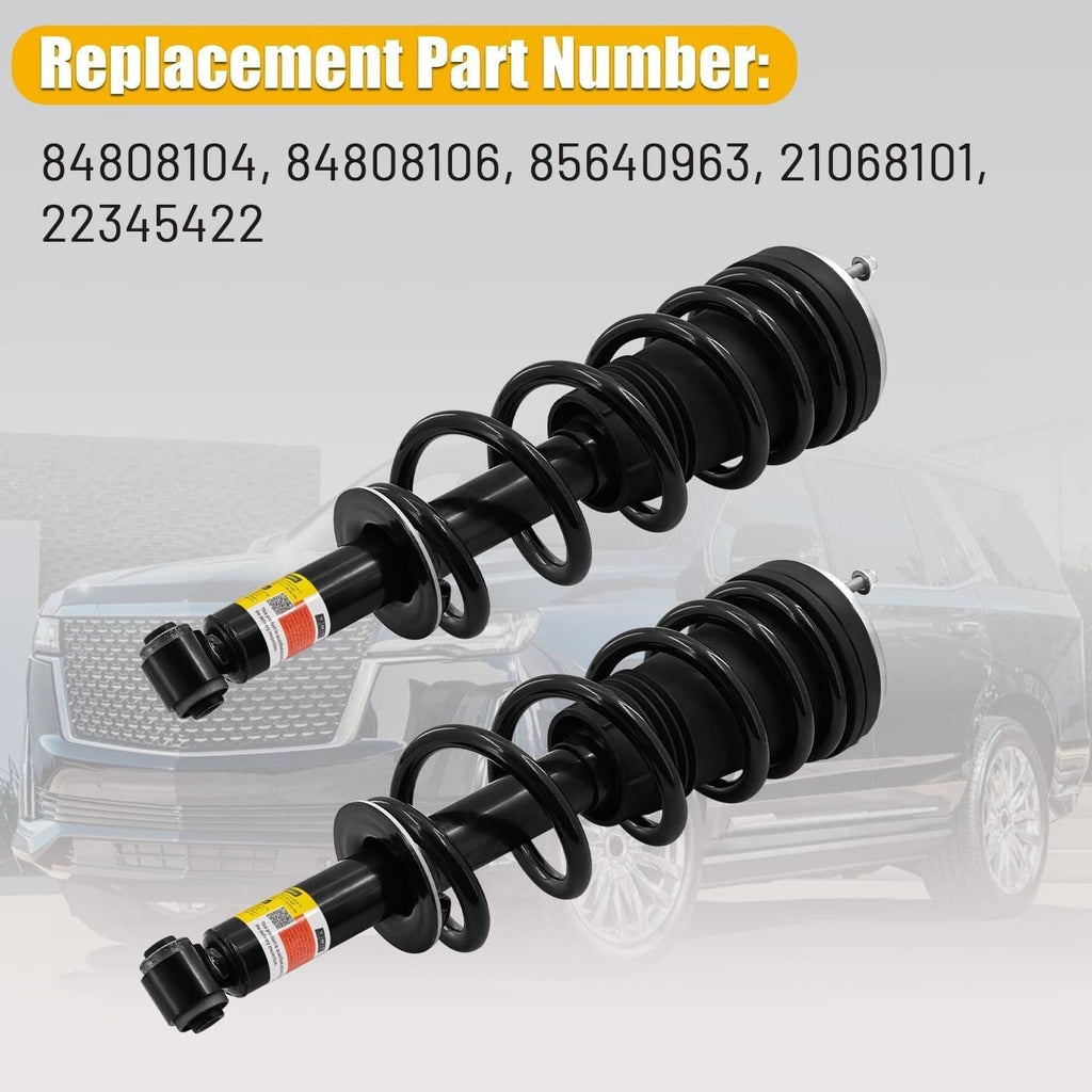 Two black shock absorber struts with coil springs and attached replacement labels