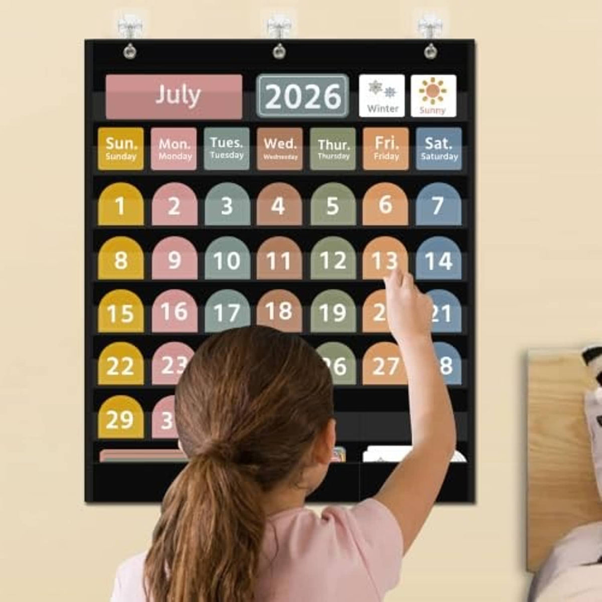 Black calendar pocket chart mounted on wall with July 2026 and day/date cards