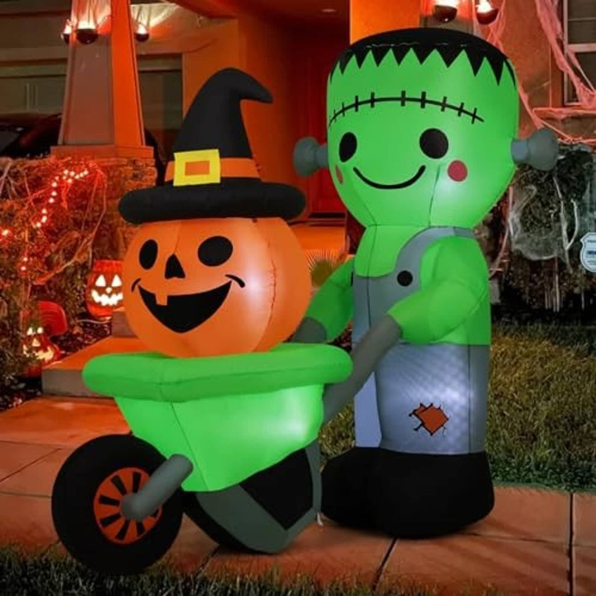 Green Frankenstein inflatable holding an orange pumpkin with black witch hat, yard Halloween decor
