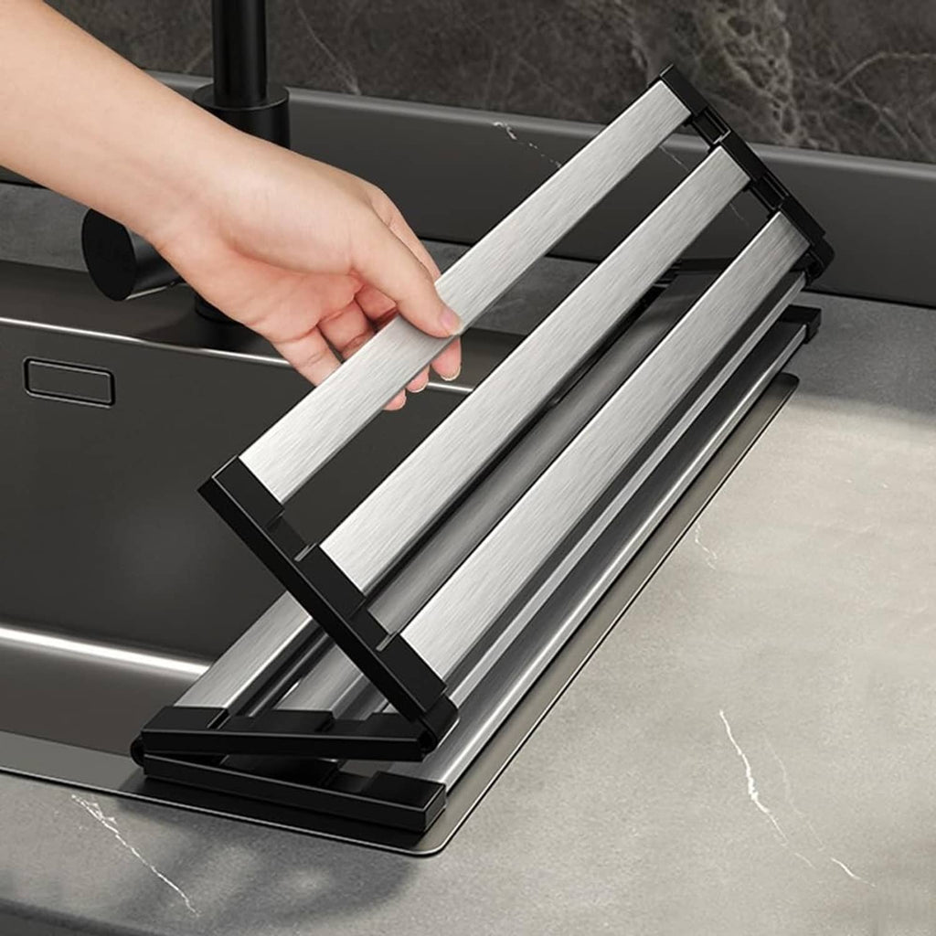 Roll-up dish drying rack with silver slats and black base, being lifted by hand