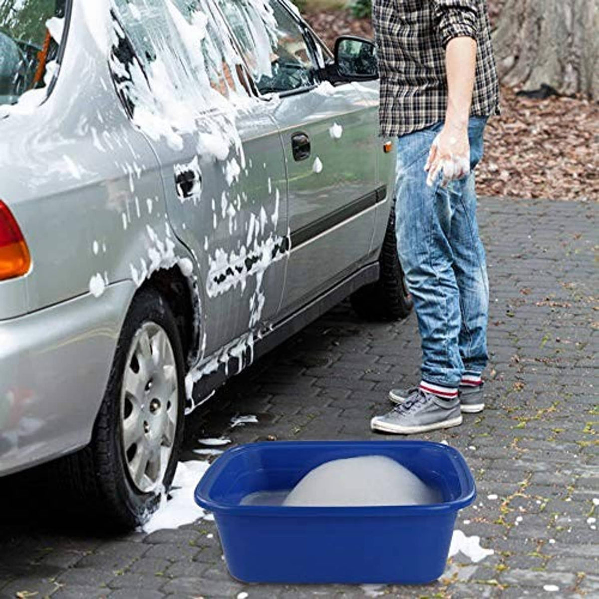 Blue plastic washing basin on driveway with water splashes