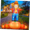 Inflatable scarecrow decoration with blue overalls and orange pumpkin base, yard display