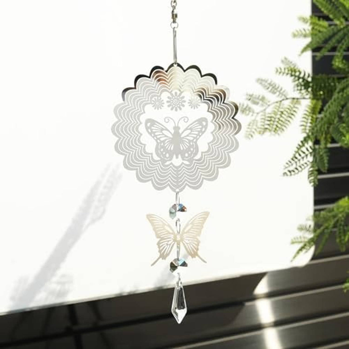 Silver decorative wind spinner featuring a sunburst medallion, butterflies, and crystal drop.
