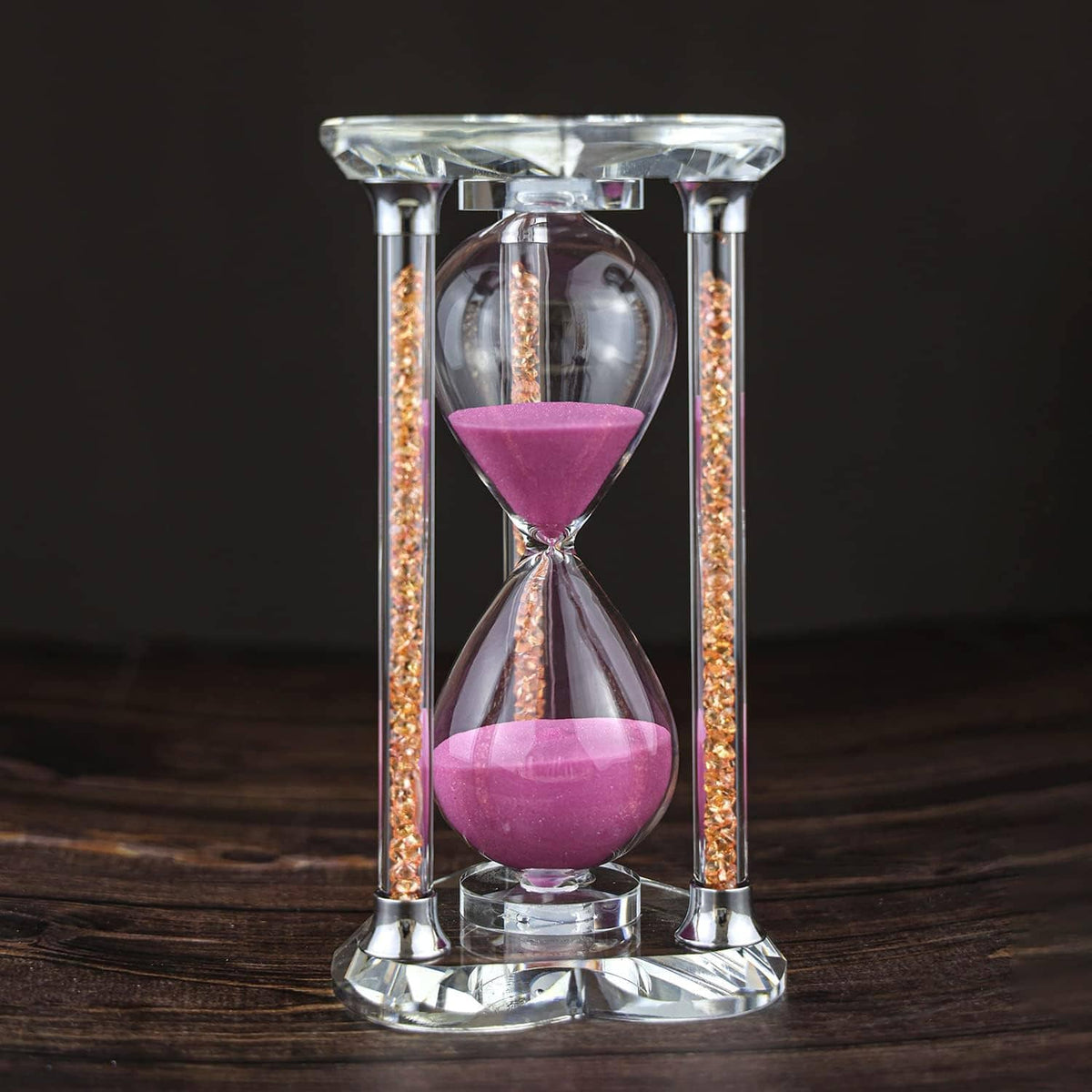 Heart-shaped hourglass with pink sand in a clear glass stand, sparkly gold side trim