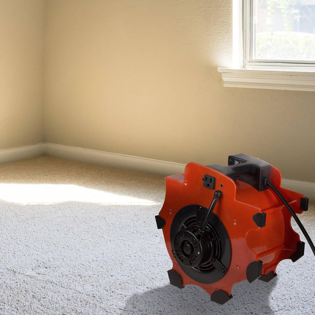 Orange blower fan dryer on carpet floor near wall and window