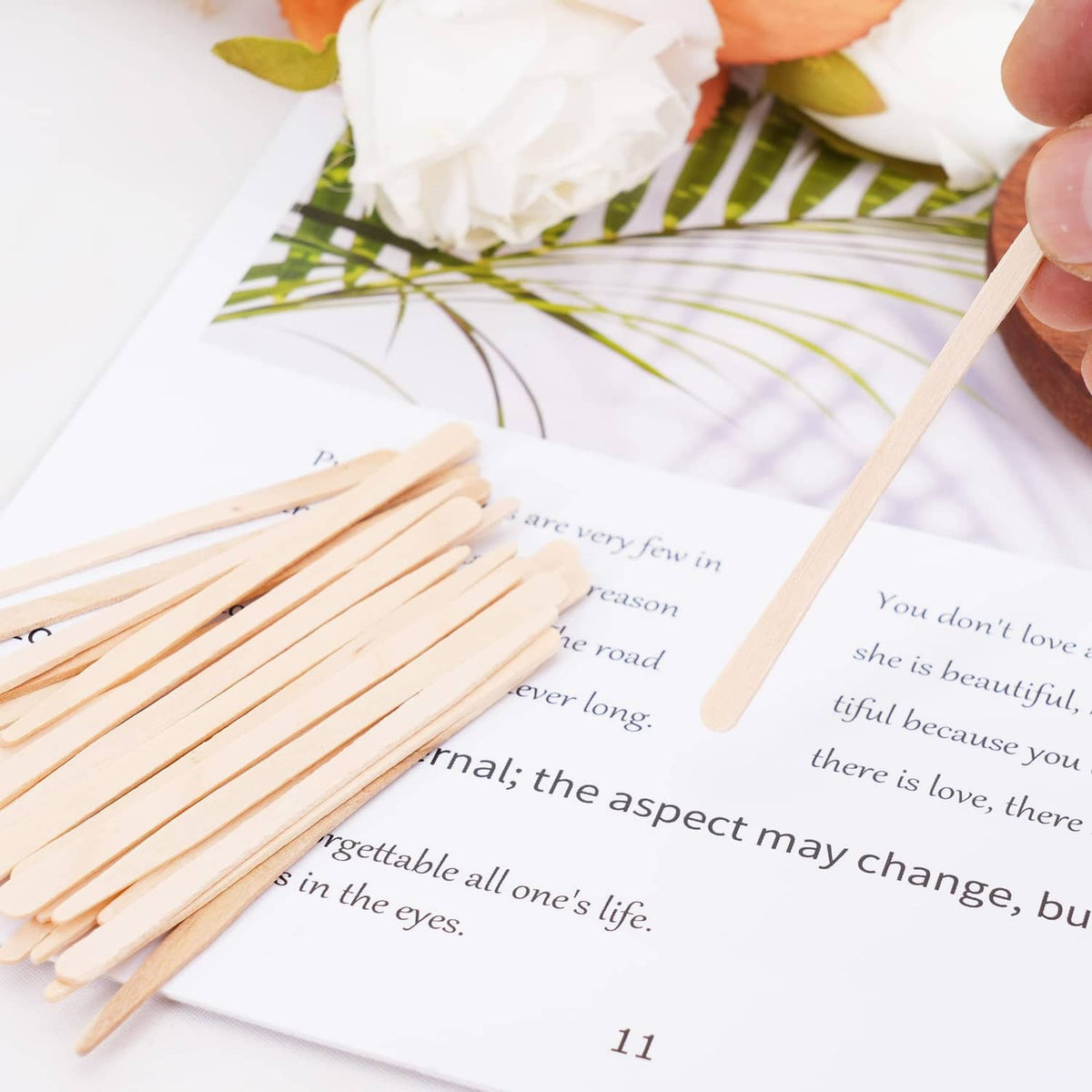 Eyebrow wax applicator sticks held above a sheet for eyebrow shaping