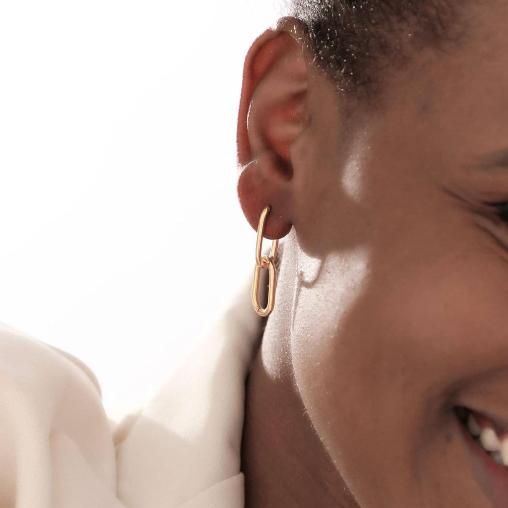 Gold rectangular hoop huggie earring, side view on ear close-up