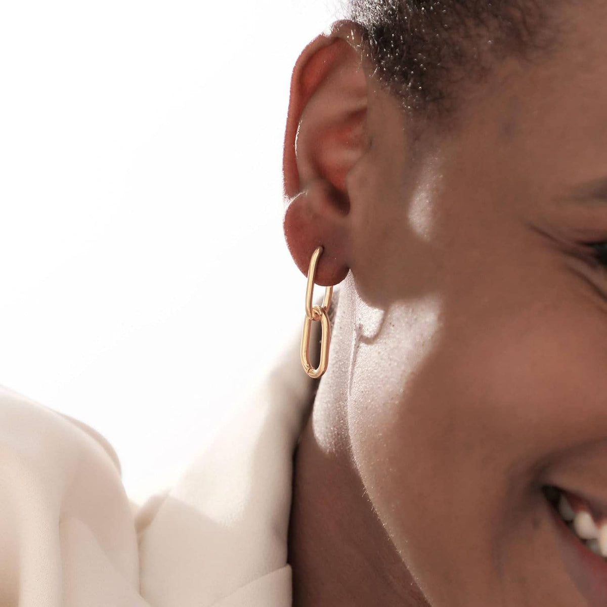 Gold rectangular hoop huggie earring, side view on ear close-up