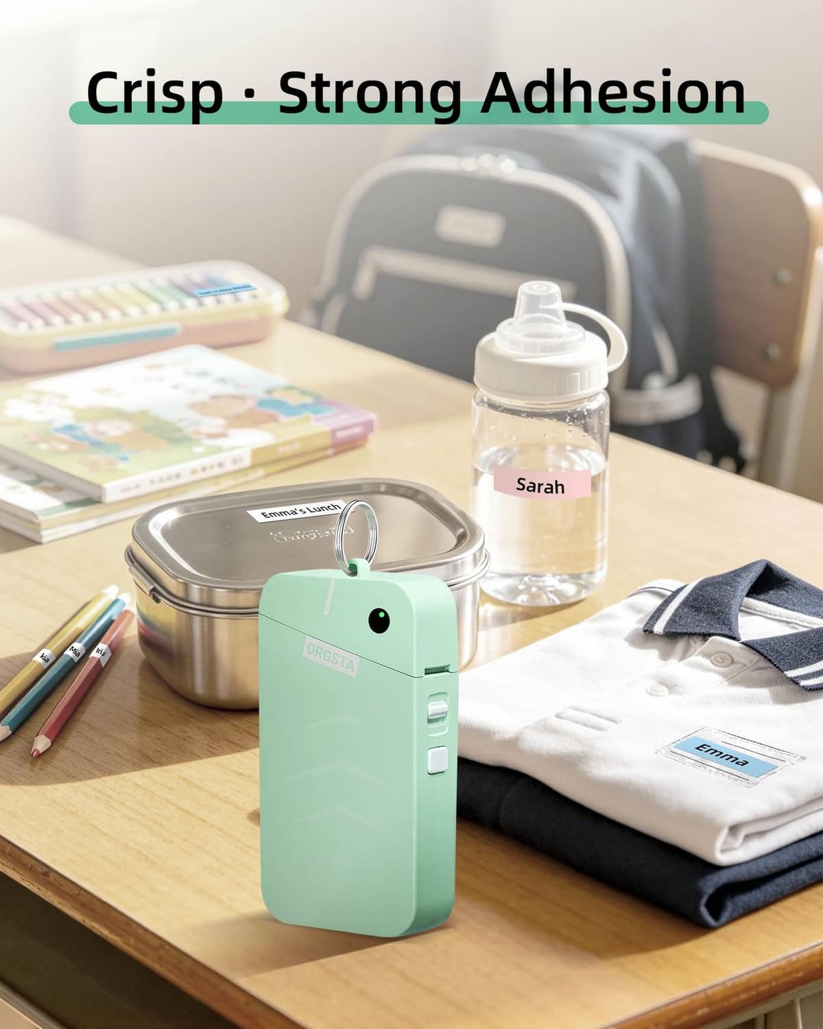 Green label maker on desk with bottle and folded fabric, compact handheld design
