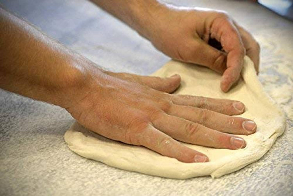 Hands shaping dough on a floured surface for baking with instant yeast.
