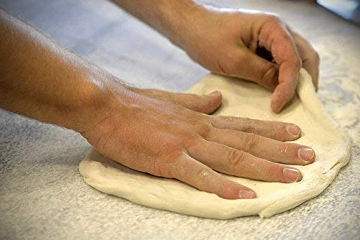 Hands shaping dough on a floured surface for baking with instant yeast.