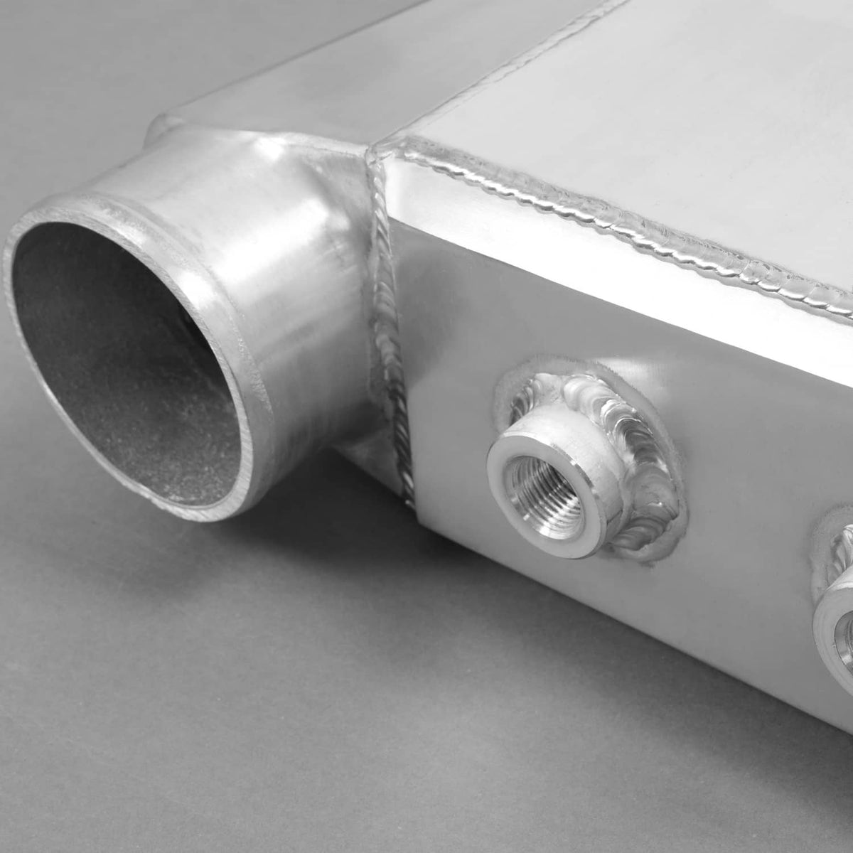 Aluminum water intercooler side end tank with large tube opening and threaded port.