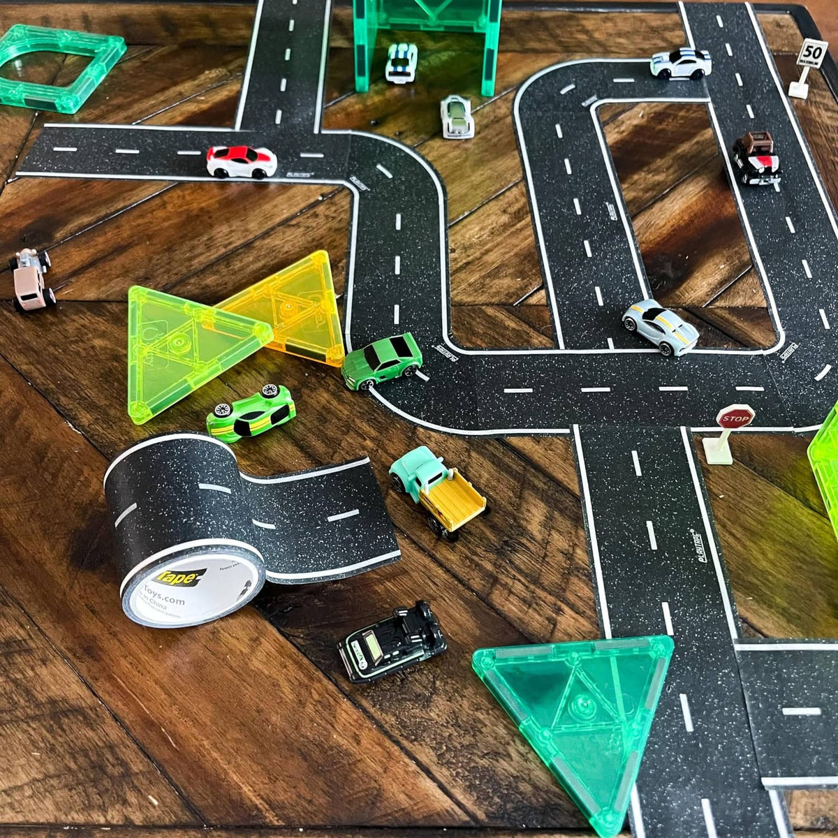 Toy road track tape with black curved lanes and white dashed line details, with cars