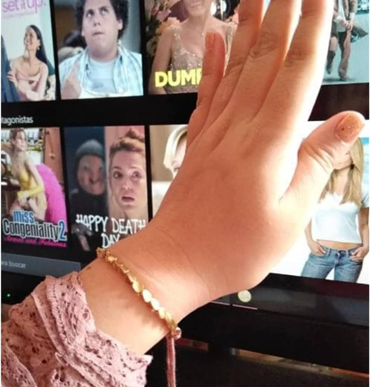 Beaded bracelet on wrist with gold-tone beads and red cord center detail.