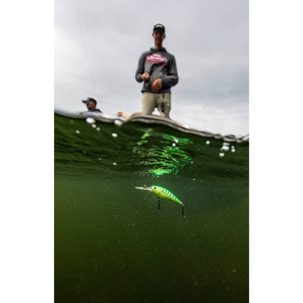 Green-yellow crankbait lure underwater with treble hooks visible