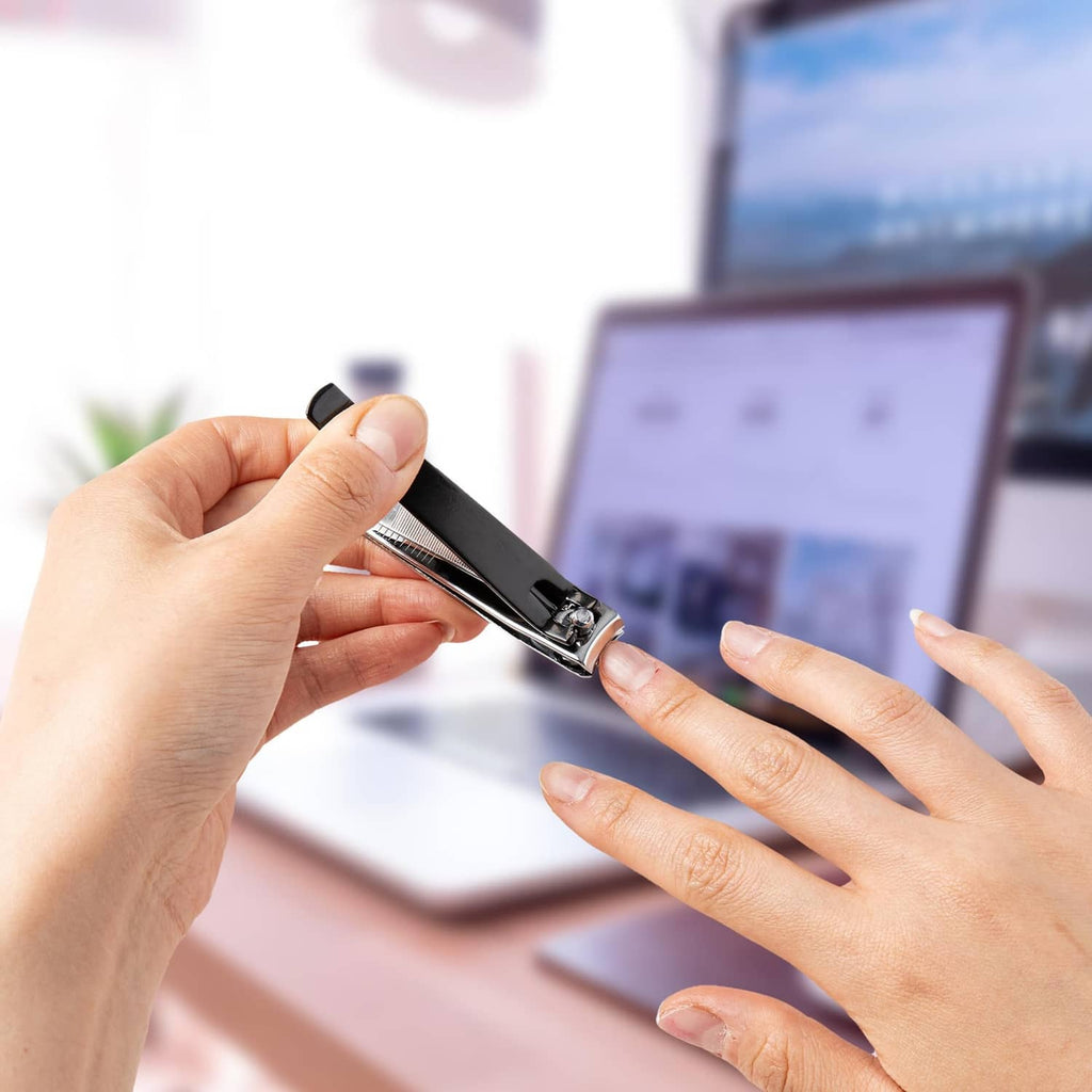 Hand holding a black nail clipper while trimming nails