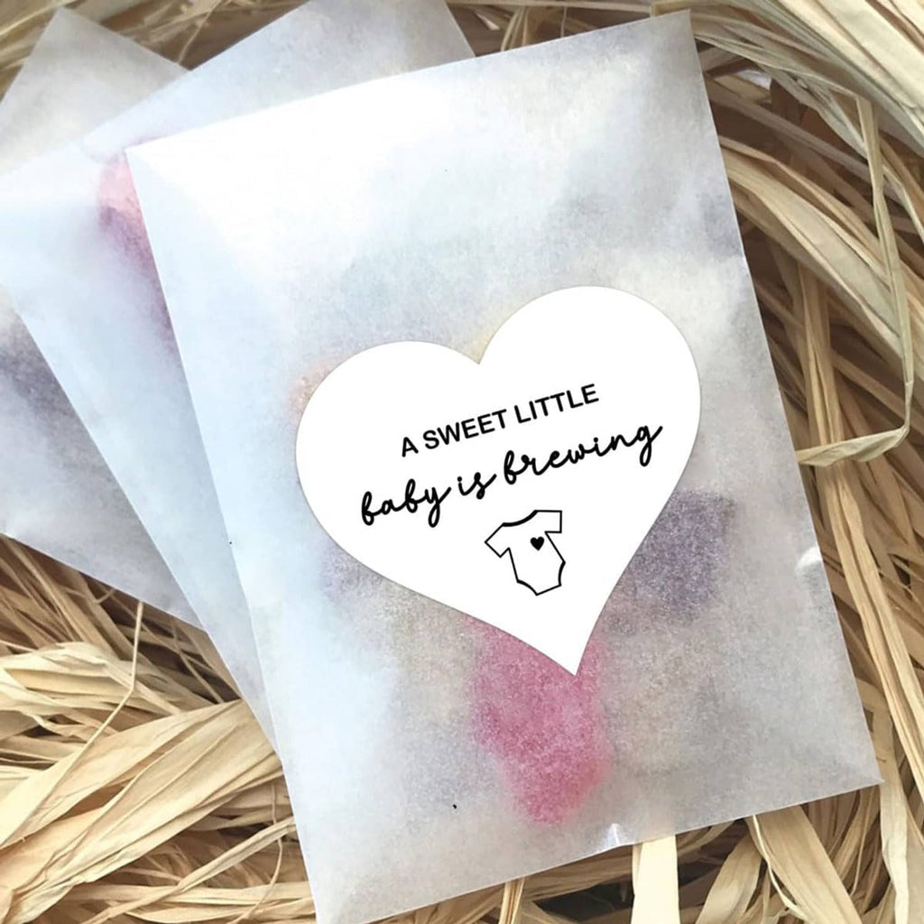 Heart-shaped sticker with “A SWEET LITTLE baby is brewing” text and baby onesie icon