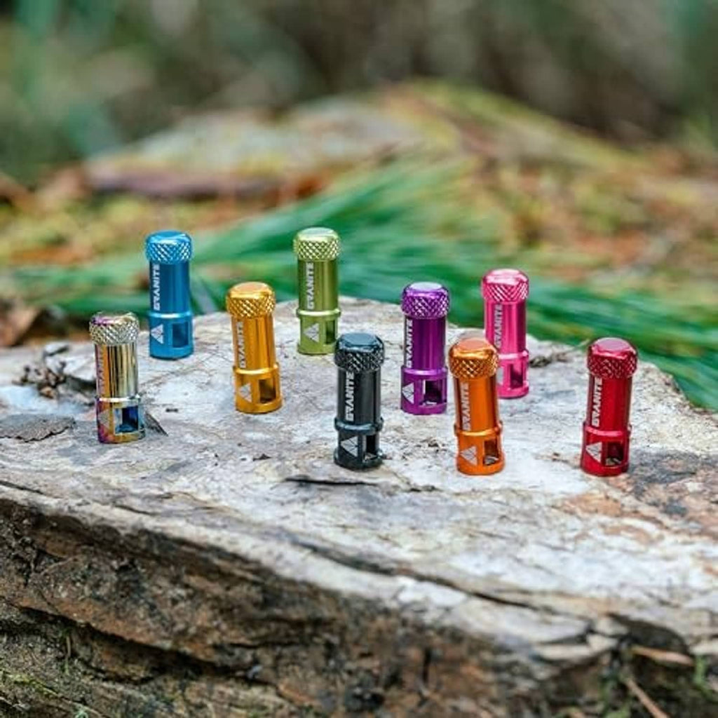 Assorted color valve core remover caps standing on a flat rock surface.