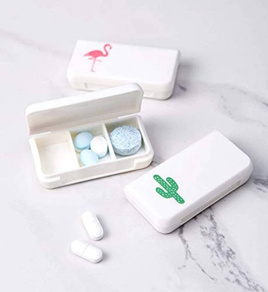 Four small white pill organizers with cactus/flamingo icons, open tray with tablets inside