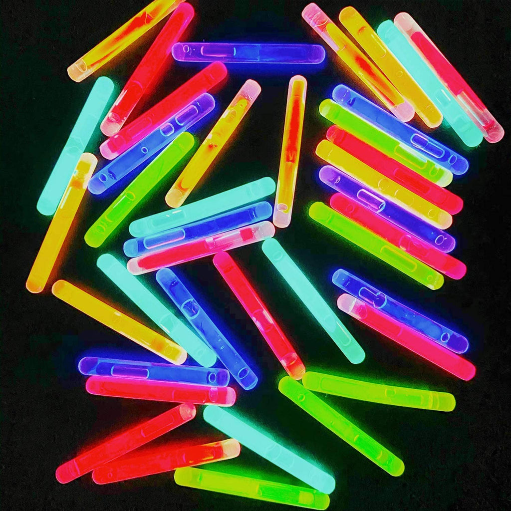 Assorted mini glow sticks scattered, glowing neon red, blue, green, yellow, and purple
