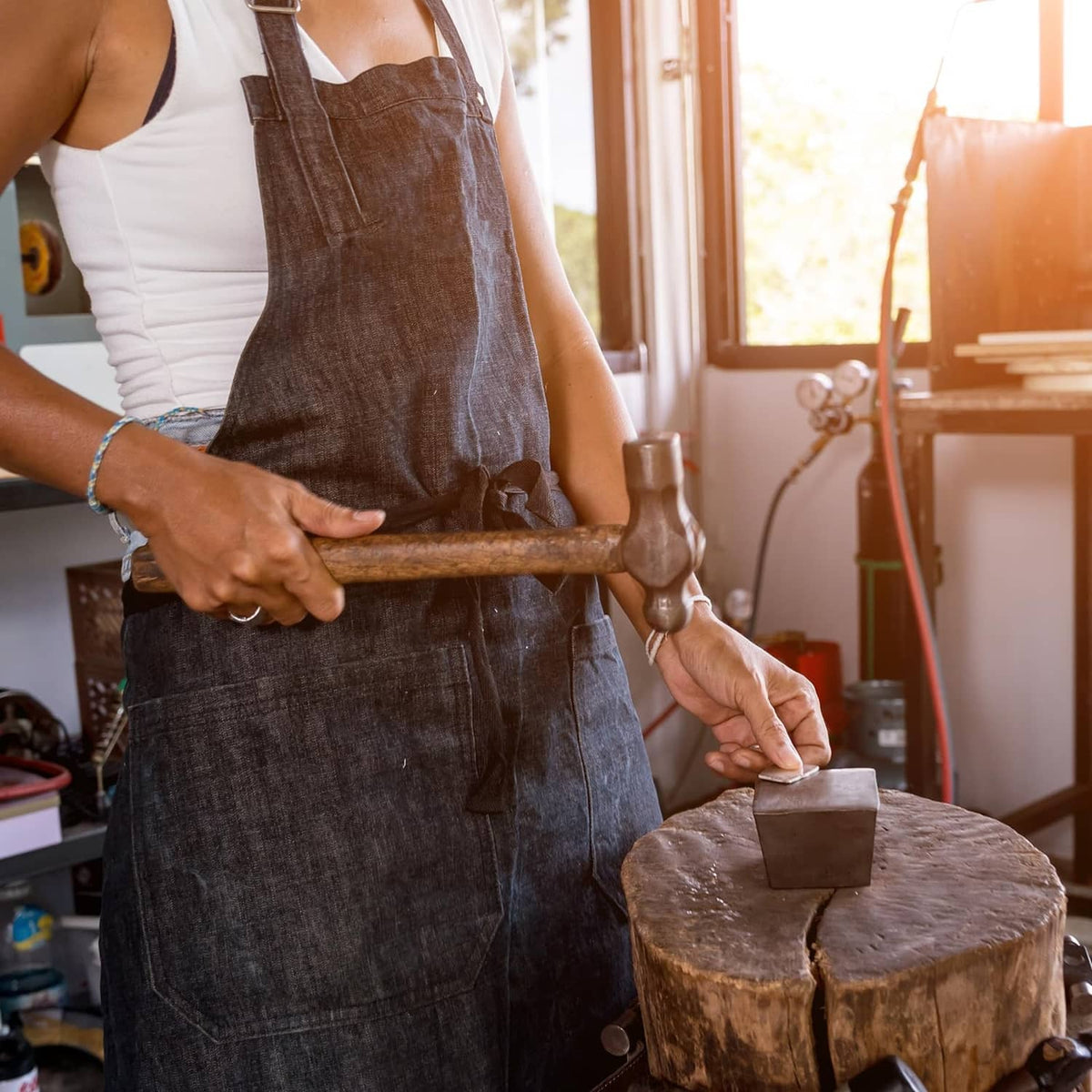 Round steel bench block in use with hammer, silver metal mallet tool