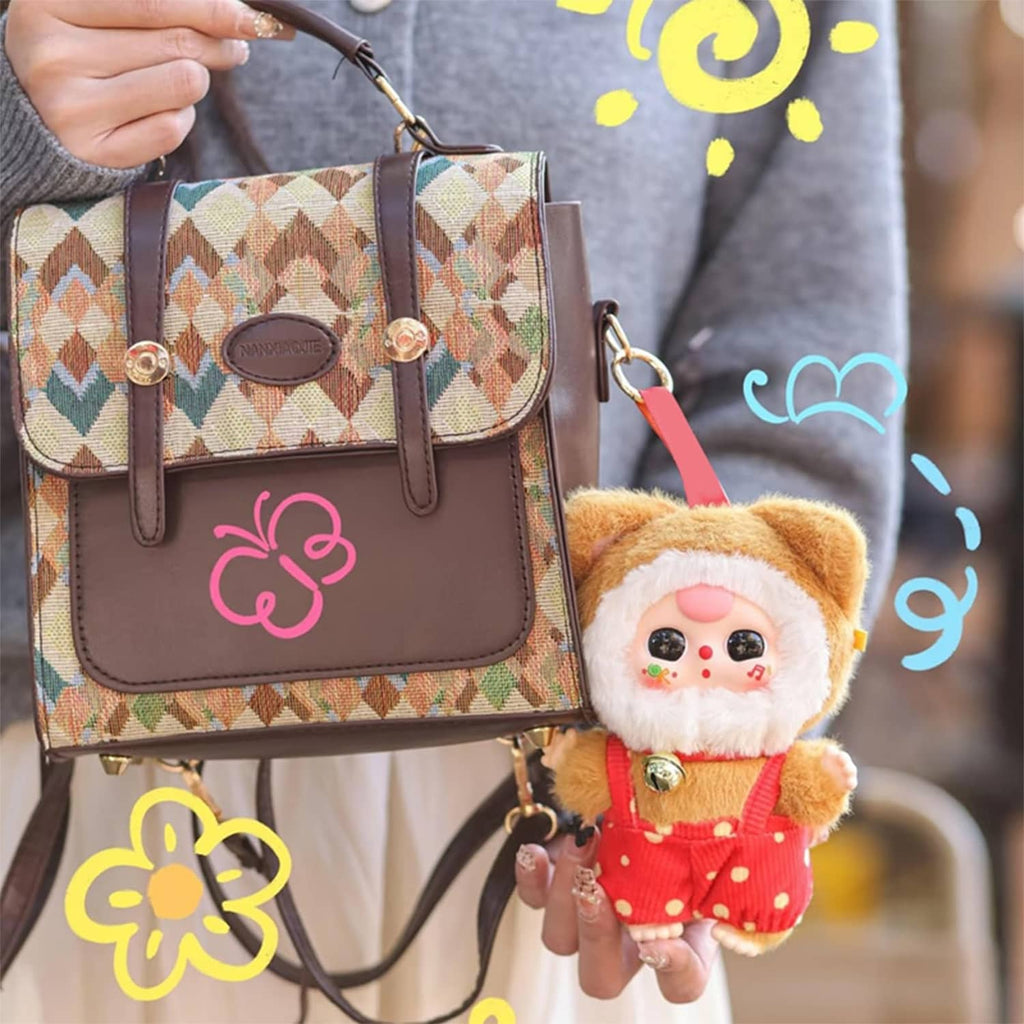 Small plush cat doll in a brown hat and orange overalls, with gold bell charm.