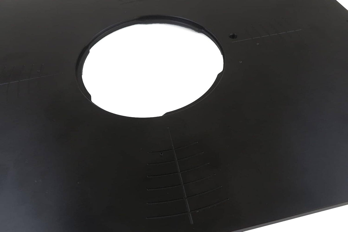 Close-up of black router table insert plate showing the large circular opening and measurement marks.