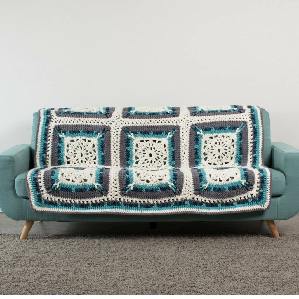 Light teal and cream crochet granny-square throw blanket on a sofa