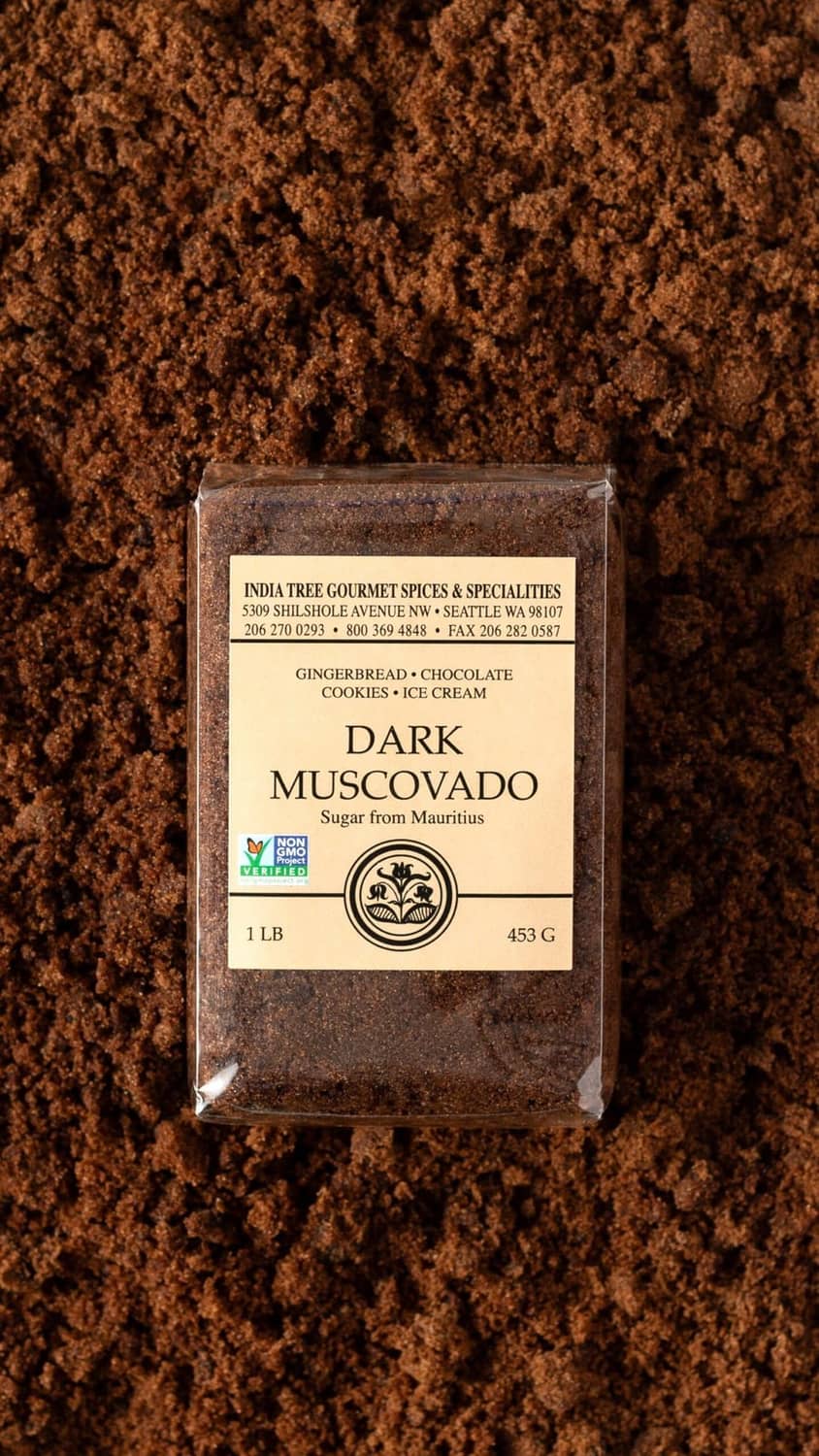 Dark muscovado sugar in bag, shown over coarse granules